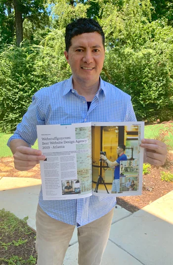 Ish Laos, founder of WebStuffGuy, holding a magazine feature about the company